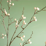 Branches of cream artificial berries against a green backdrop