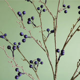 Branches of blue artificial berries against a green backdrop