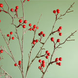 Branches of red artificial berries against a green backdrop