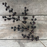 Faux glossy black berry stem laid on rustic wooden boards