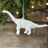 Silver long-neck dinosaur decoration hanging from a fir branch