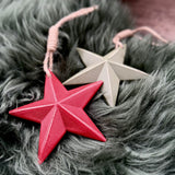 Red wooden star decoration beside a sage green star
