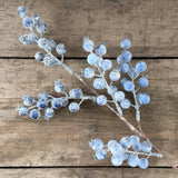 Faux frosted blueberry stem with pale icy blue berries on wooden boards