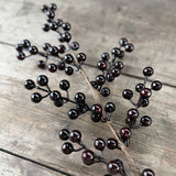 Close-up of shiny black artificial berries on a wire stem