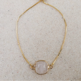 Clear Quartz square slider bracelet laid flat on linen with gold box chain
