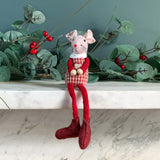 Red sitting mouse in a striped top dangling its legs over a mantelpiece