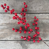 Faux glossy red berry stem laid on rustic wooden boards