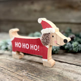 Wooden sausage dog decoration in a red 'Ho ho ho!' outfit and Santa hat