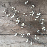 Faux cream berry branch stem on rustic wooden boards