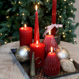 Lit cherry red sparkly cone candles on a tray with baubles