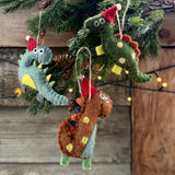 Three felt hanging dinosaur decorations in Santa hats on a Christmas tree