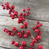 Close-up of shiny red artificial berries on a wire stem