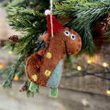 Brown spotty felt dinosaur in a Santa hat hanging on a Christmas tree