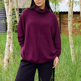 Model wearing the merlot mini cable roll neck jumper outdoors