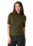 Model wearing the short sleeve knit turtleneck in olive with grey jeans