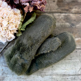 Olive green faux fur mittens on a rustic wooden table with dried hydrangeas