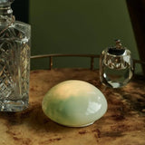 Pale Green LED pebble light on a table beside a glass decanter