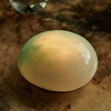 Pale Green LED rechargeable glass pebble light glowing on a wooden table