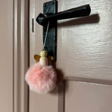 Pink pompom angel decoration hanging from a door handle