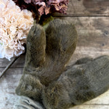 Pair of olive green faux fur mittens beside dried hydrangeas