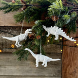 Three silver hanging dinosaur decorations on a Christmas tree