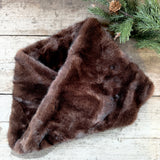 Deep brown faux fur snood on a wooden table with pine sprigs