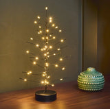 Black Mini Festive LED tree lit up beside a ceramic vase
